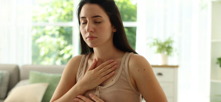 Panic attack vs anxiety attack: woman with her hands on her chest breathing to stay calm